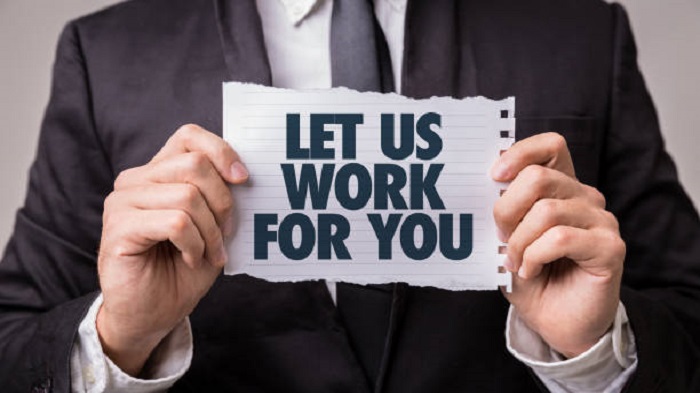 une personne qui tient un papier avec une affirmation "Let us work for you"-externalisation d'entreprise-Buroservices