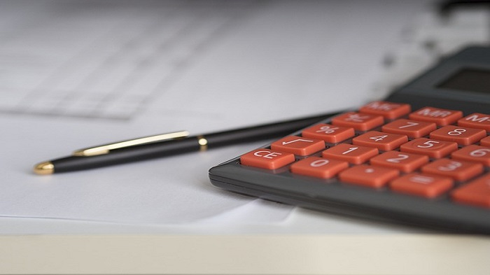 une calculatrice à côté d'un stylo et d'un document - avantages fiscaux - Buro Services