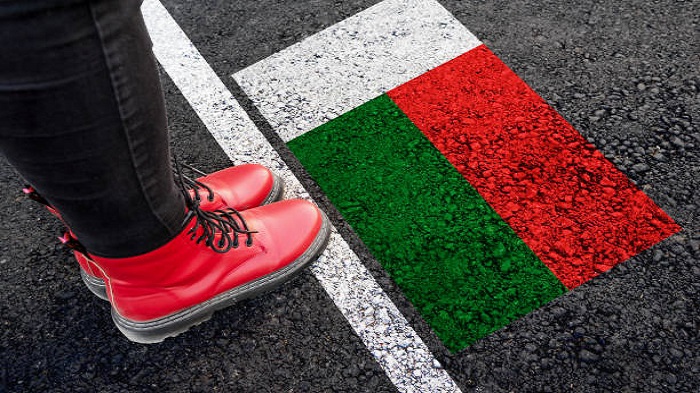 une femme avec des bottes se tenant devant une peinture du drapeau de Madagascar - société de domiciliation à Madagascar - Buro Services