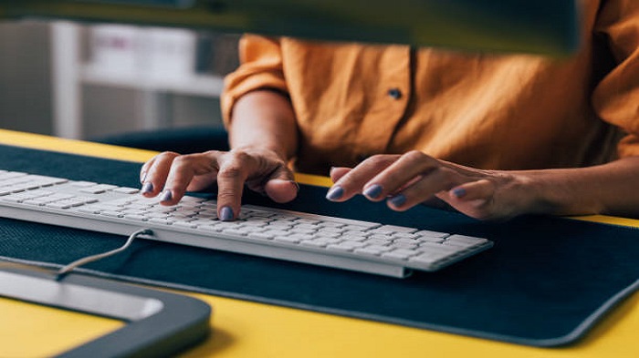 les mains d'une secrétaire tapant sur les claviers d'un ordinateur - société de domiciliation entreprise - Buro Services 