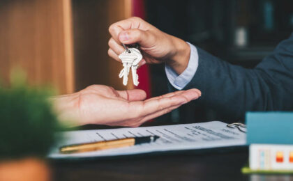 un homme d'affaires remettant les clés de la maison à une femme et signant un contrat dans un bureau - domiciliation d'entreprises - Buro Services