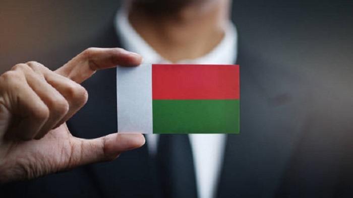 Homme d'affaires tenant une carte du drapeau de Madagascar - Madagascar en portage salarial - Buro Services