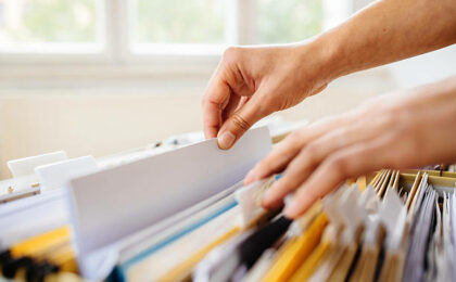 mains fouillant dans un classeur - externaliser la gestion administrative - Buro Services
