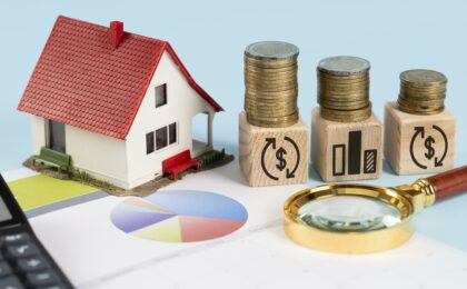 une maquette de maisons et des piles d'argent sur une table - coût réel d'une domiciliation d'entreprise - Buro Services