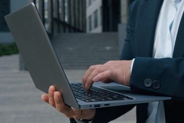 un homme d'affaires anonyme tapant sur un ordinateur - créer une société à Madagascar - Buro Services