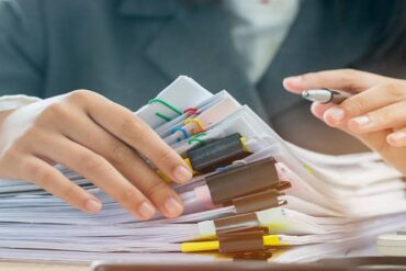 Une femme d'affaires travaille dans un bureau, rangeant des documents - externalisation gestion administrative - Buro Services