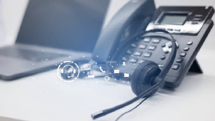 Gros plan sur un casque et un téléphone noirs avec une icône virtuelle de fonctionnement 24h/24 et 7j/7 - externaliser les fonctions supports - Buro Services