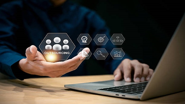 Main d'un homme d'affaires tenant une icône d'externalisation sur un écran virtuel - externalisation de services - Buro Services