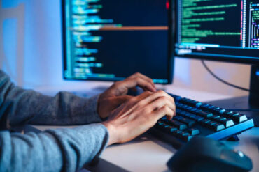 les mains d'un ingénieur de prompts asiatique développant une application de codage à partir de données logicielles - externaliser une équipe de développeurs à Madagascar - Buro Services
